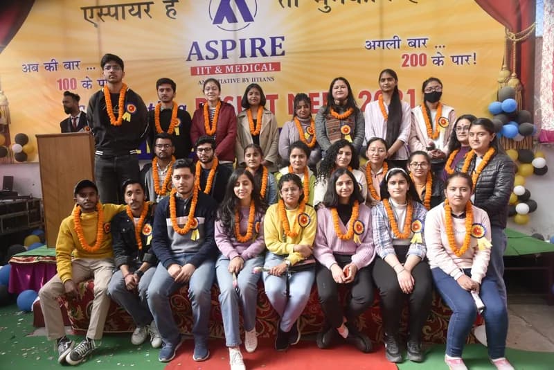 Garlanded students posing with faculty at an Aspire felicitation event in front of a Hindi banner