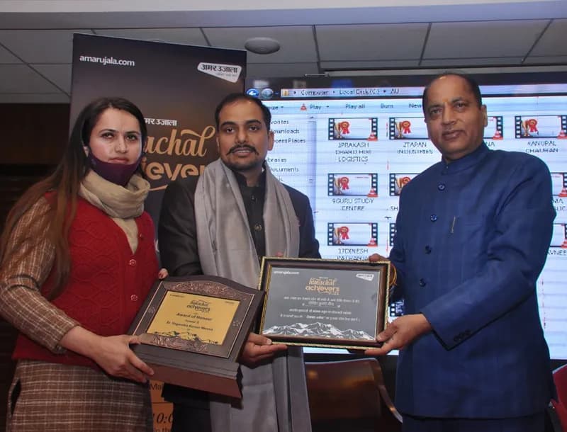 A woman and a man holding award plaques beside a dignitary at the Himachal Achievers 2021 event (Amar Ujala backdrop)