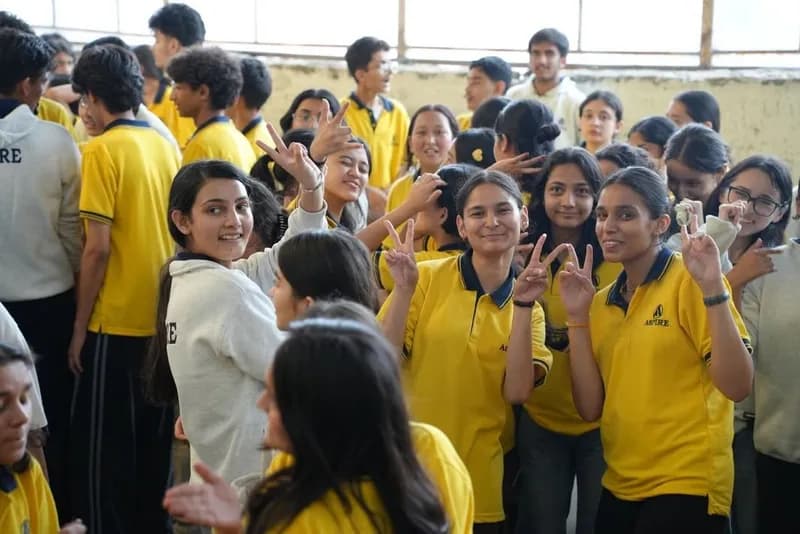 Crowd of cheerful Aspire students in yellow T-shirts showing victory signs at a celebration