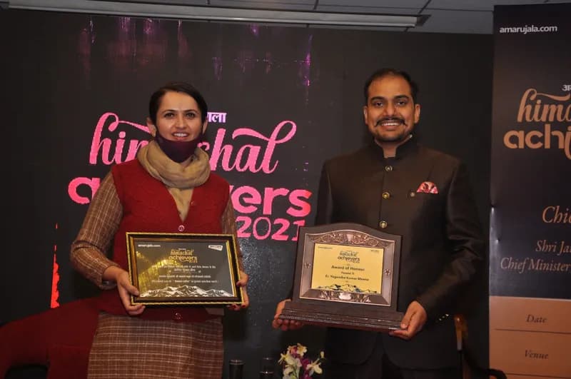 Two Aspire representatives holding award plaques in front of the Himachal Achievers 2021 backdrop
